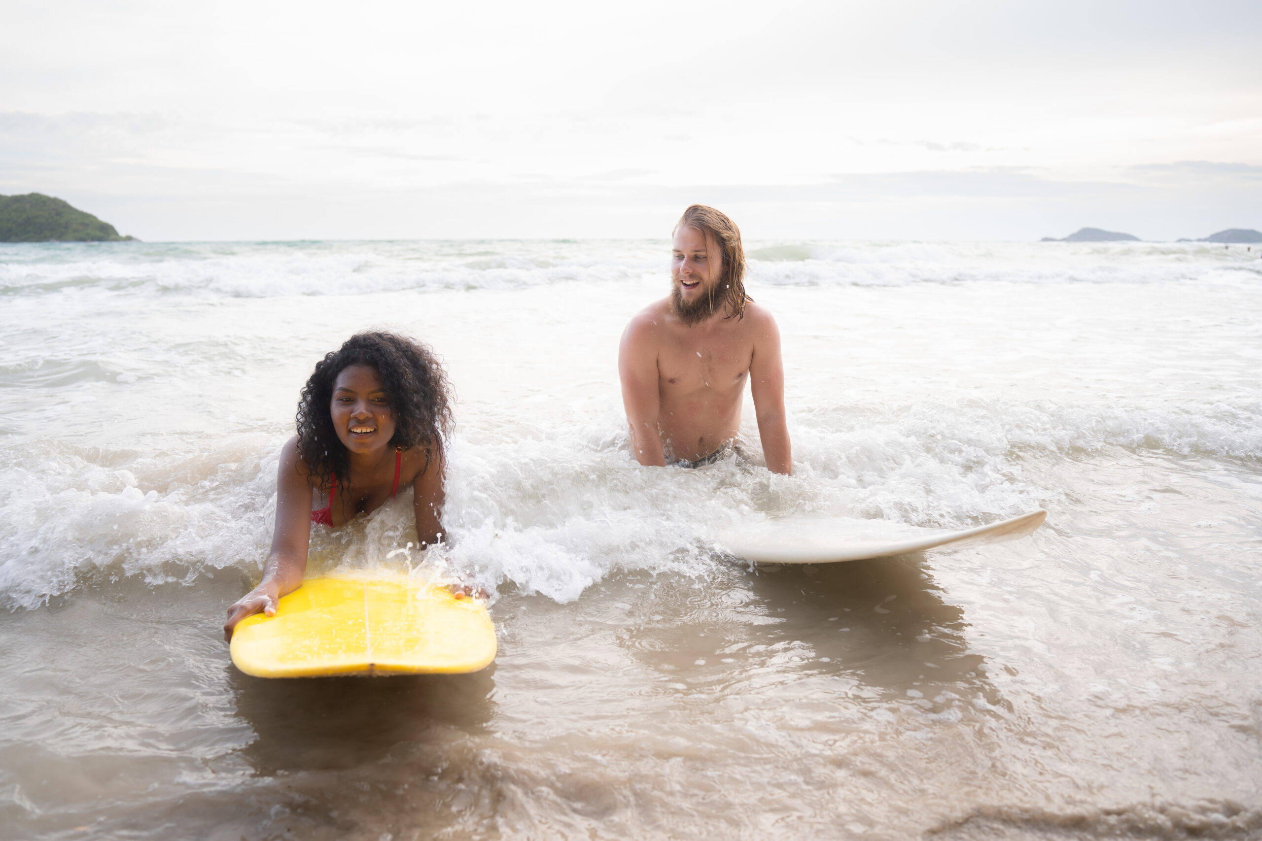 Jeune homme et femme s'amusant avec une planche de surf dans l'océan par une journée ensoleillée