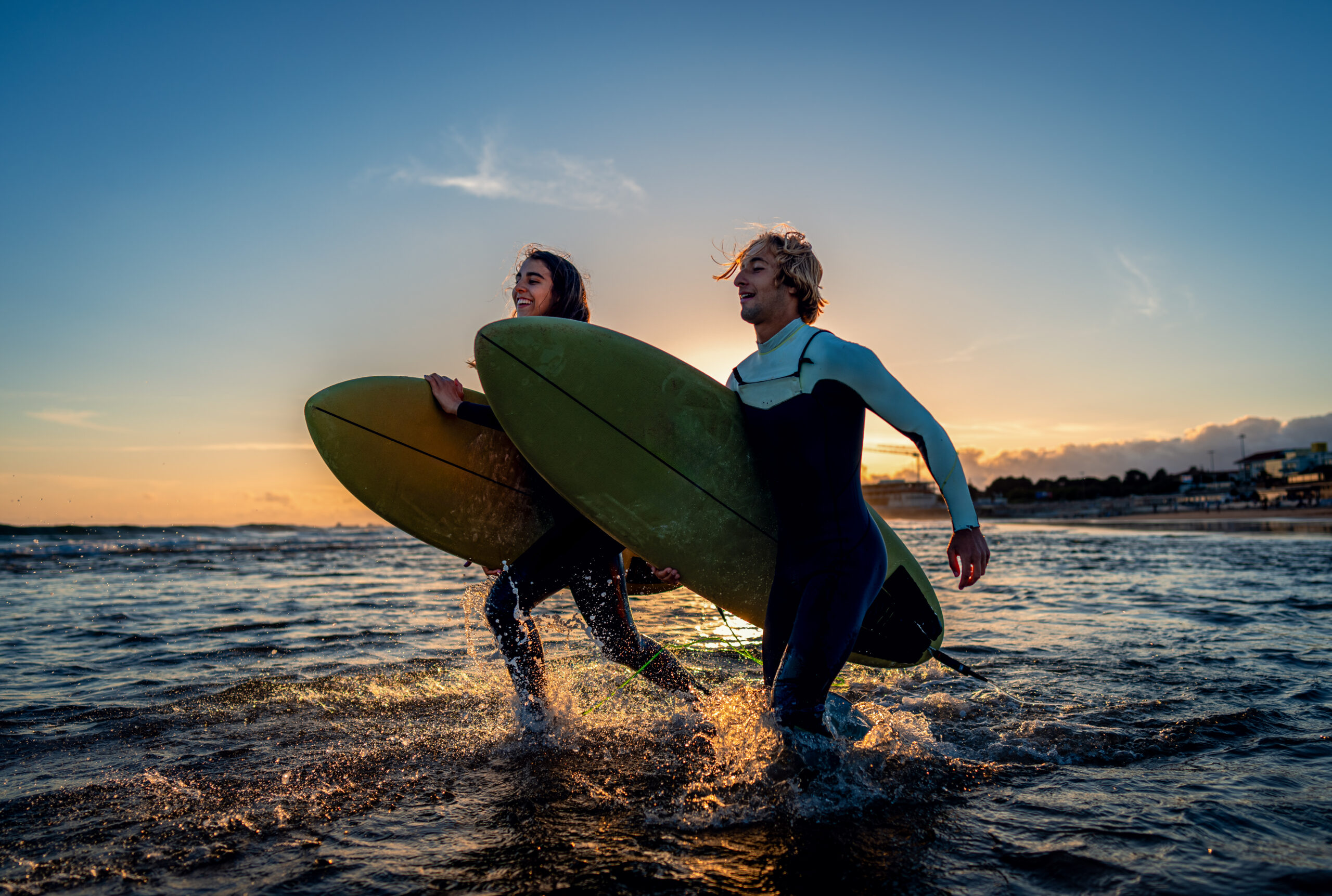 Deux surfeurs avec planche de surf se préparent à frapper les vagues au coucher du soleil.